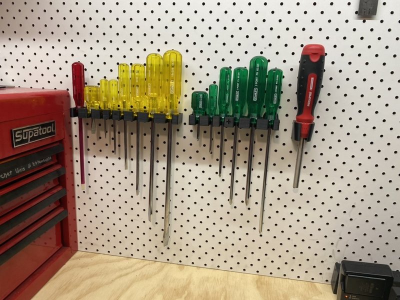 Colour-coded screwdriver holders installed on a workshop pegboard